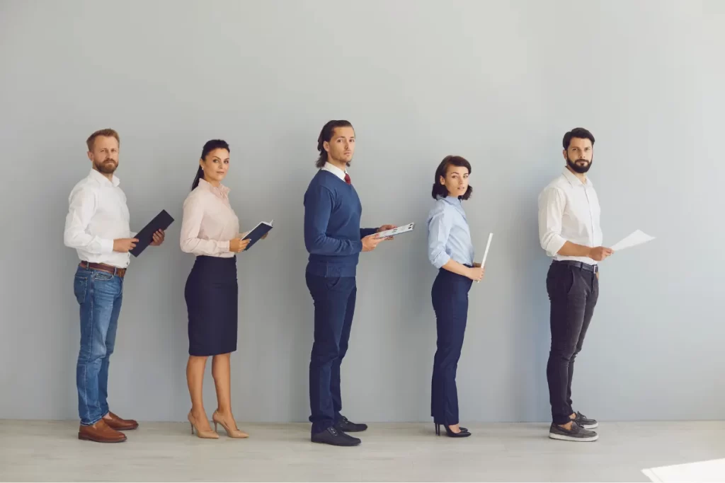 Job candidates standing in line, holding resumes and waiting for interviews at Moving Heads Recruitment Agency