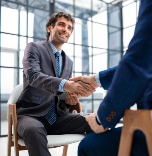 Smiling businessman shaking hands during a meeting at Moving Heads Recruitment Agency