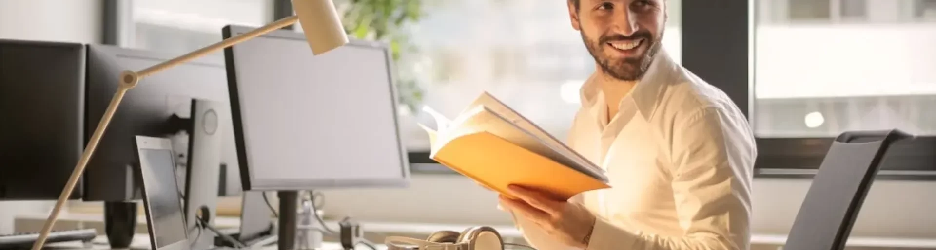 Smiling professional reading documents at his desk in a modern office at Moving Heads Recruitment Agency